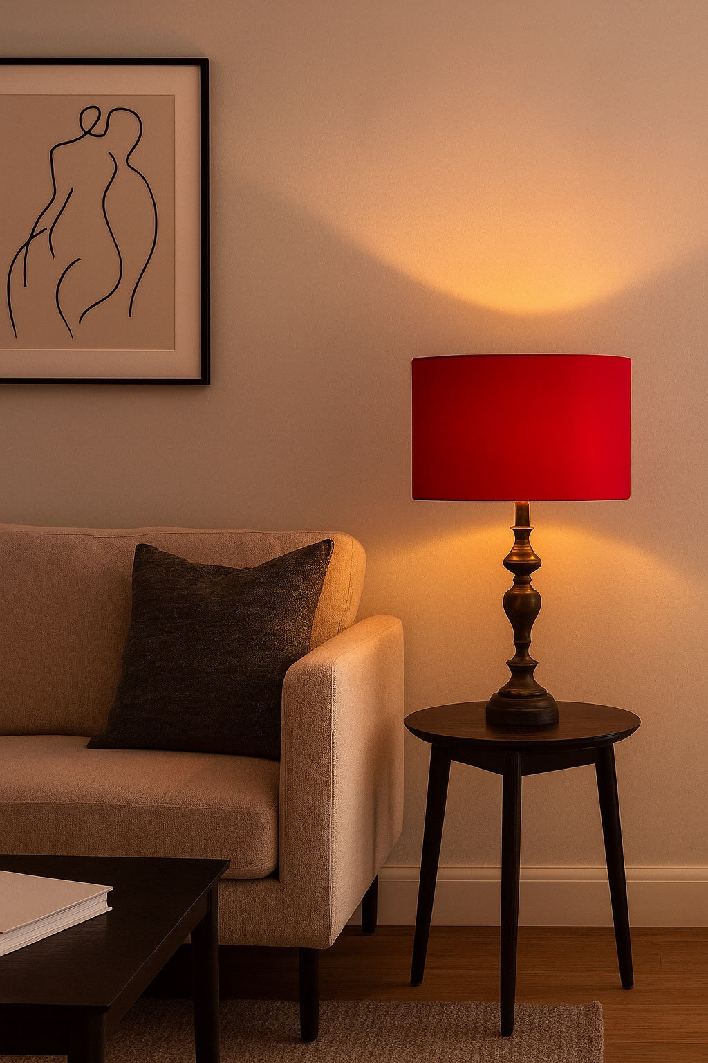 Lampe de chevet avec abat-jour ovale en velours rouge Rubinia, diffusant une lumière dorée chaleureuse dans un salon moderne.