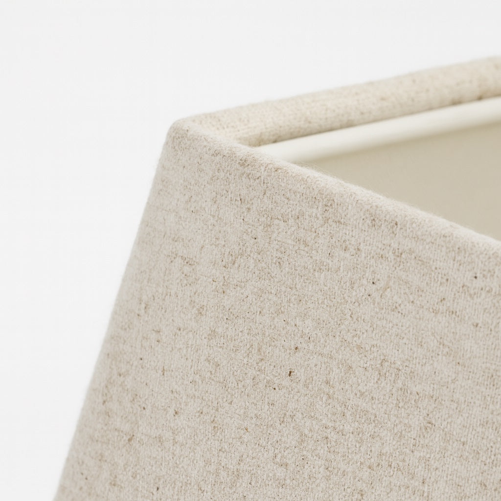 Gros plan sur la texture en lin naturel d’un abat-jour pyramide blanc pour lampe moderne et épurée.