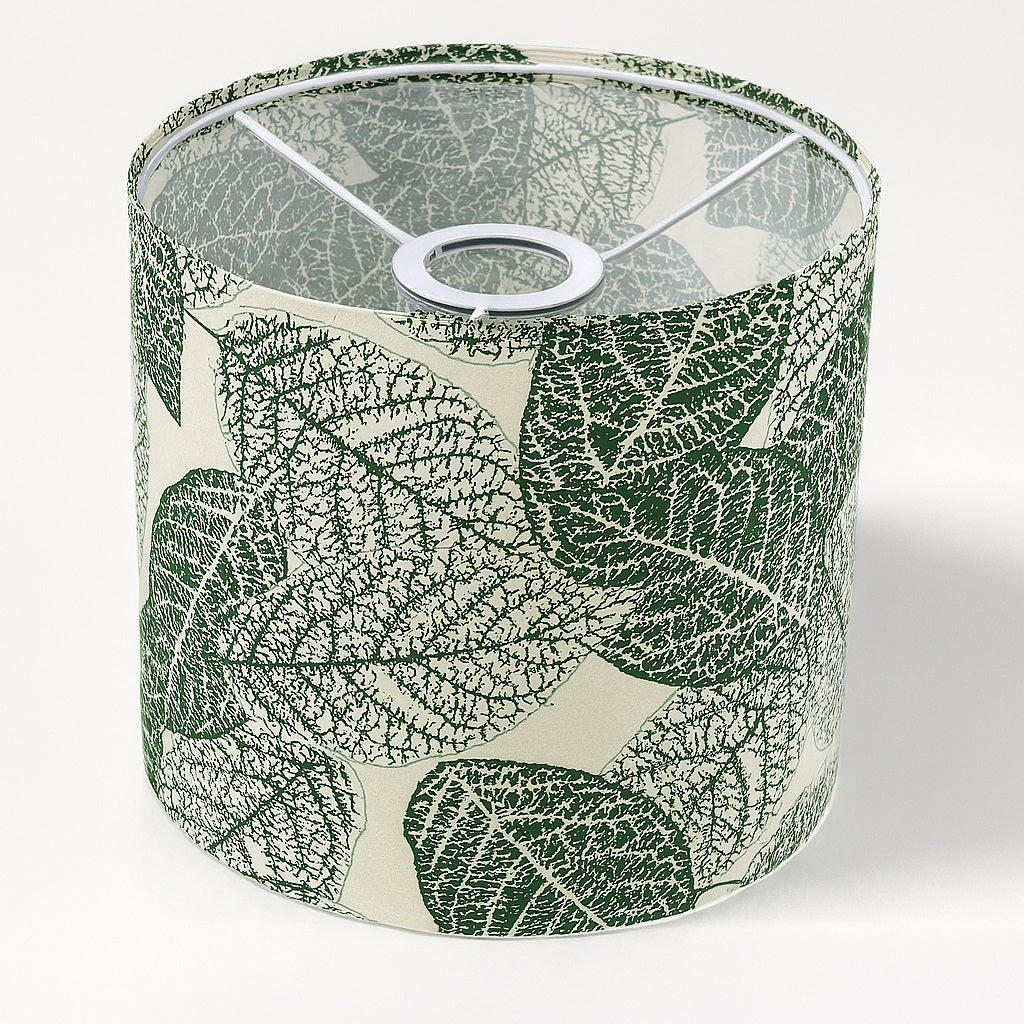 Abat-jour cylindrique en tissu à motif feuillage vert sur fond beige, vue de dessus avec structure métallique intérieure blanche.