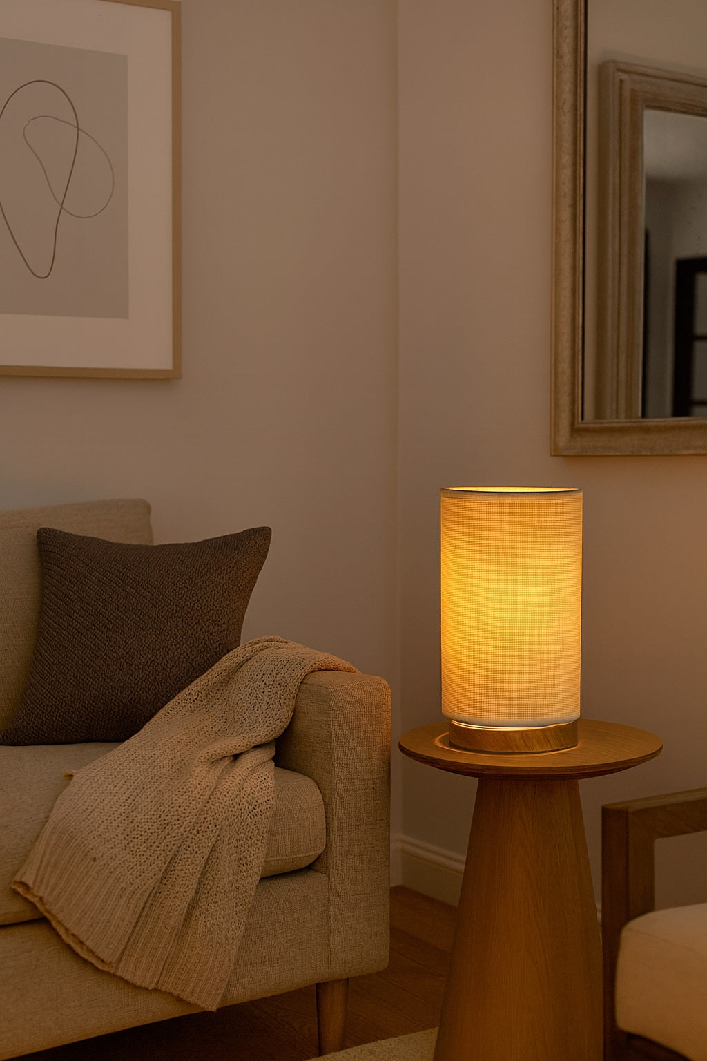 Abat-jour en tissu cylindrique diffusant une lumière chaude dans un salon cosy et chaleureux