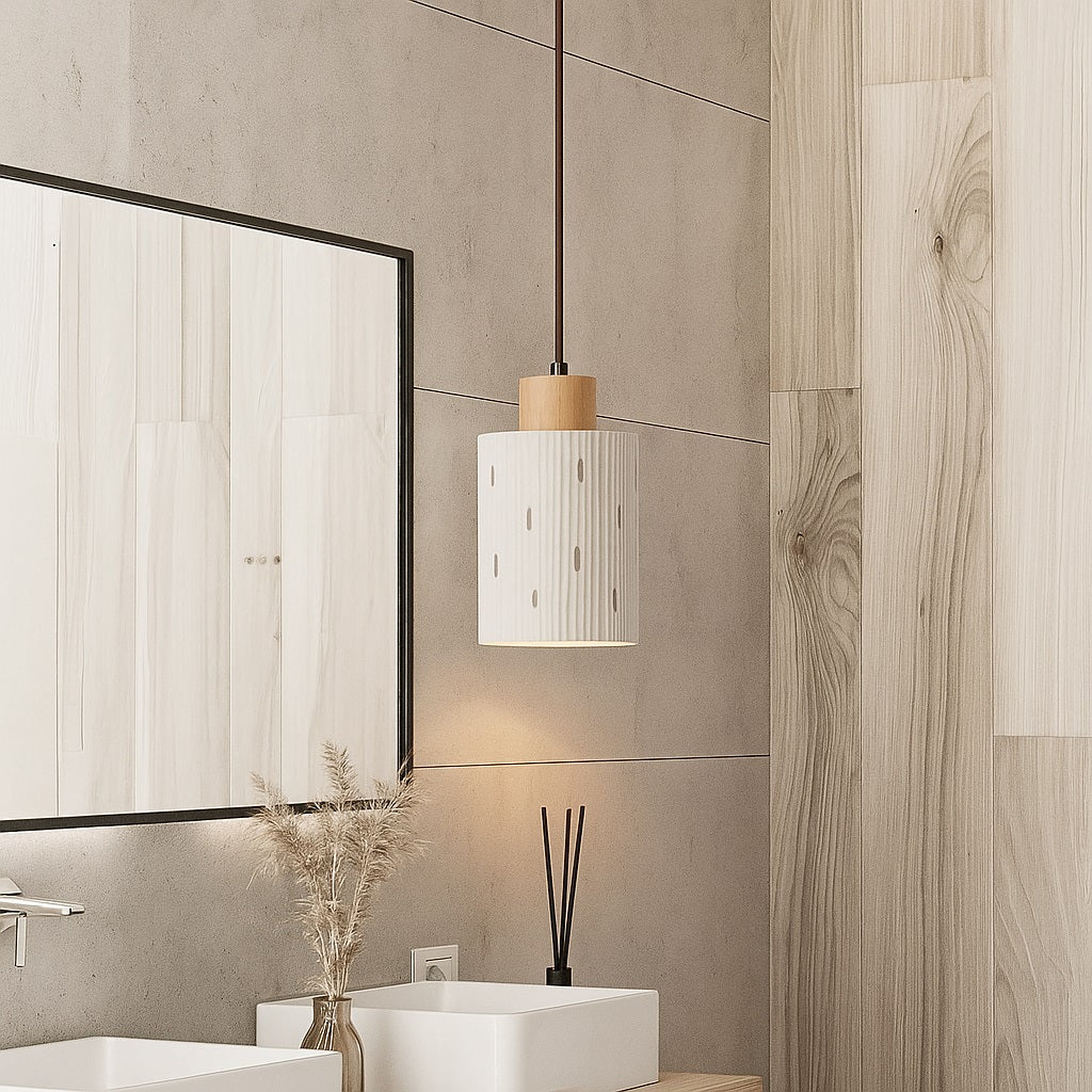 Suspension cylindrique en ciment strié au-dessus d’un meuble vasque, design naturel et lumière douce dans une salle de bain.