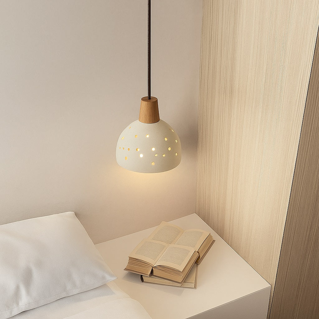 Suspension en ciment perforé au-dessus d’une table de chevet, lumière douce et design naturel pour chambre moderne.