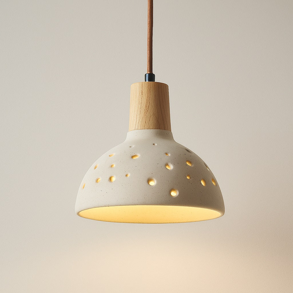Abat-jour suspension en ciment perforé et bois clair, lumière douce et effet constellation, style naturel et contemporain.