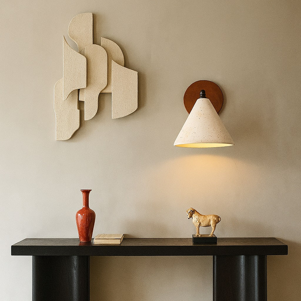 Applique murale en travertin allumée, fixée au mur au-dessus d’une console décorative dans un intérieur sobre.