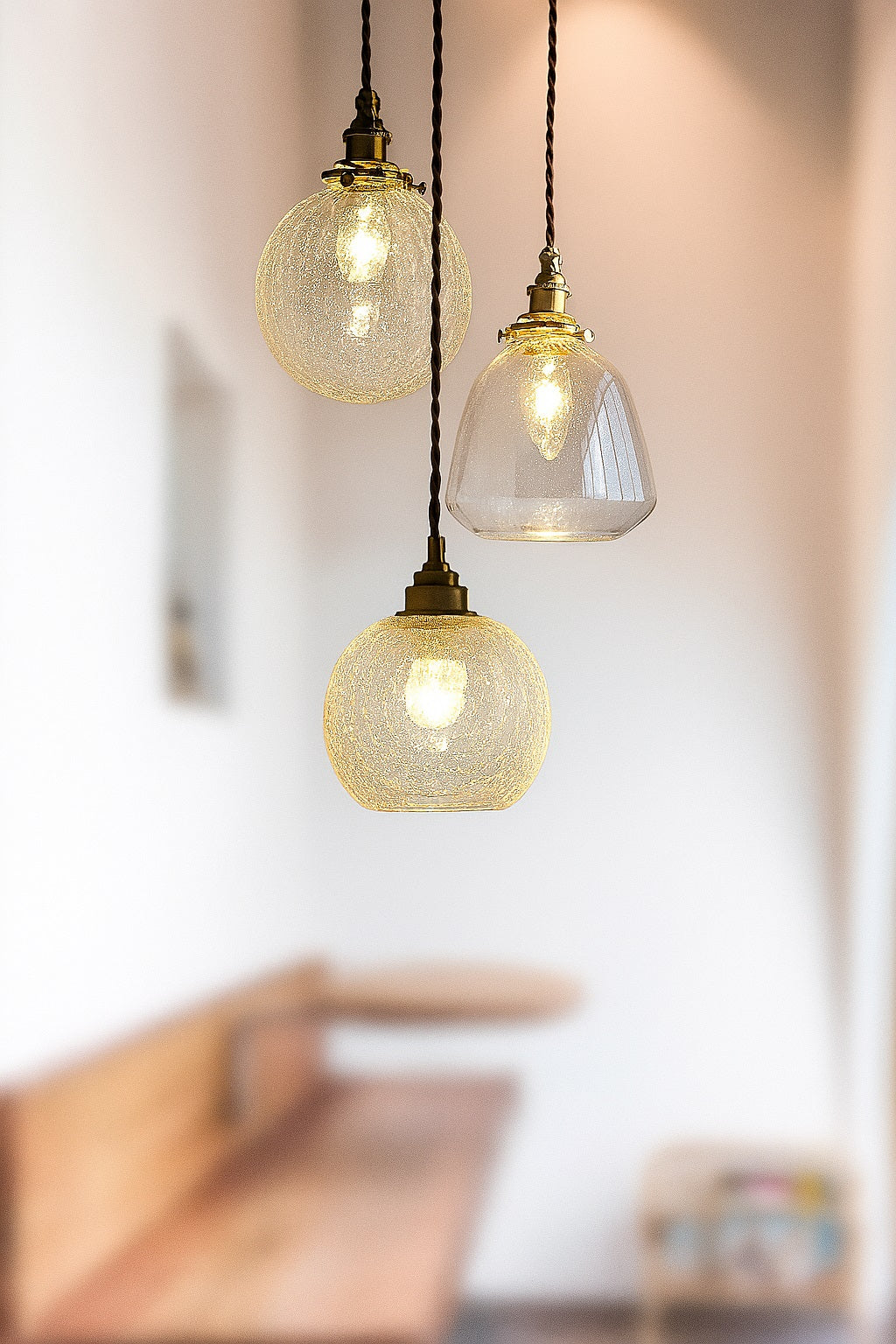 Suspensions en verre nettes brillent au premier plan, avec un flouté d'un coin repas chaleureux.