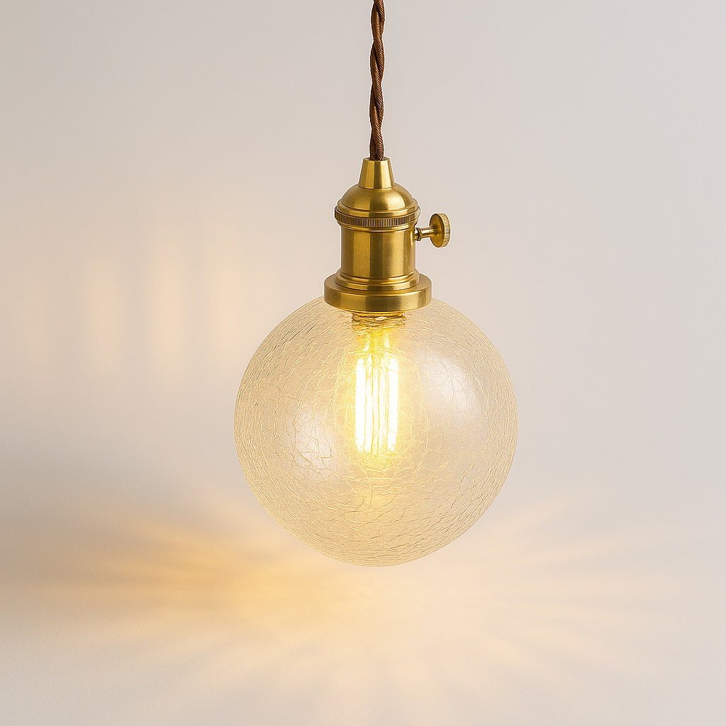 Abat-jour suspension en verre taillé diamant, lumière chaude diffusée sur fond clair, douille laiton brillante.