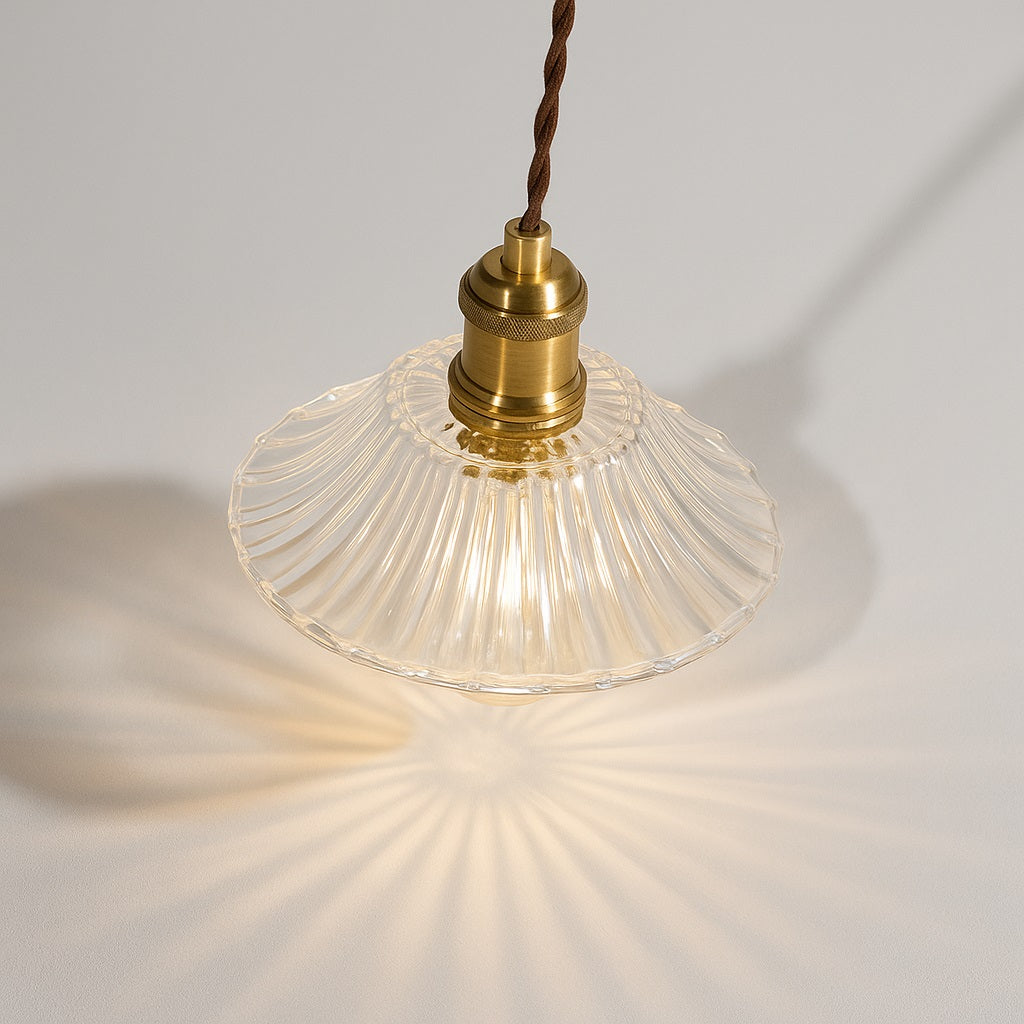 Lampe suspendue vue du dessus à 45°, abat-jour en verre nervuré transparent, lumière décorative, douille dorée.