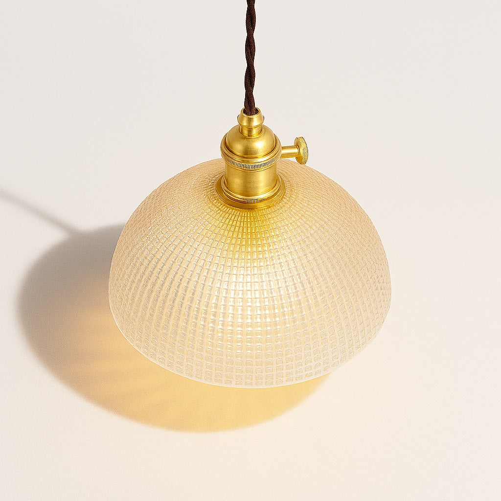 Lampe suspendue vue du dessus à 45°, abat-jour en verre bombé quadrillé, lumière chaleureuse, douille laiton.