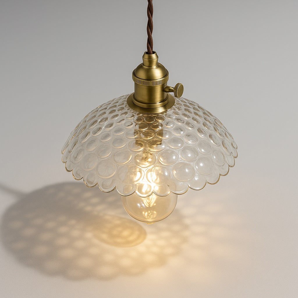 Lampe suspendue vue du dessus à 45°, abat-jour bombé en verre transparent à motifs bulles, douille laiton, lumière chaude.