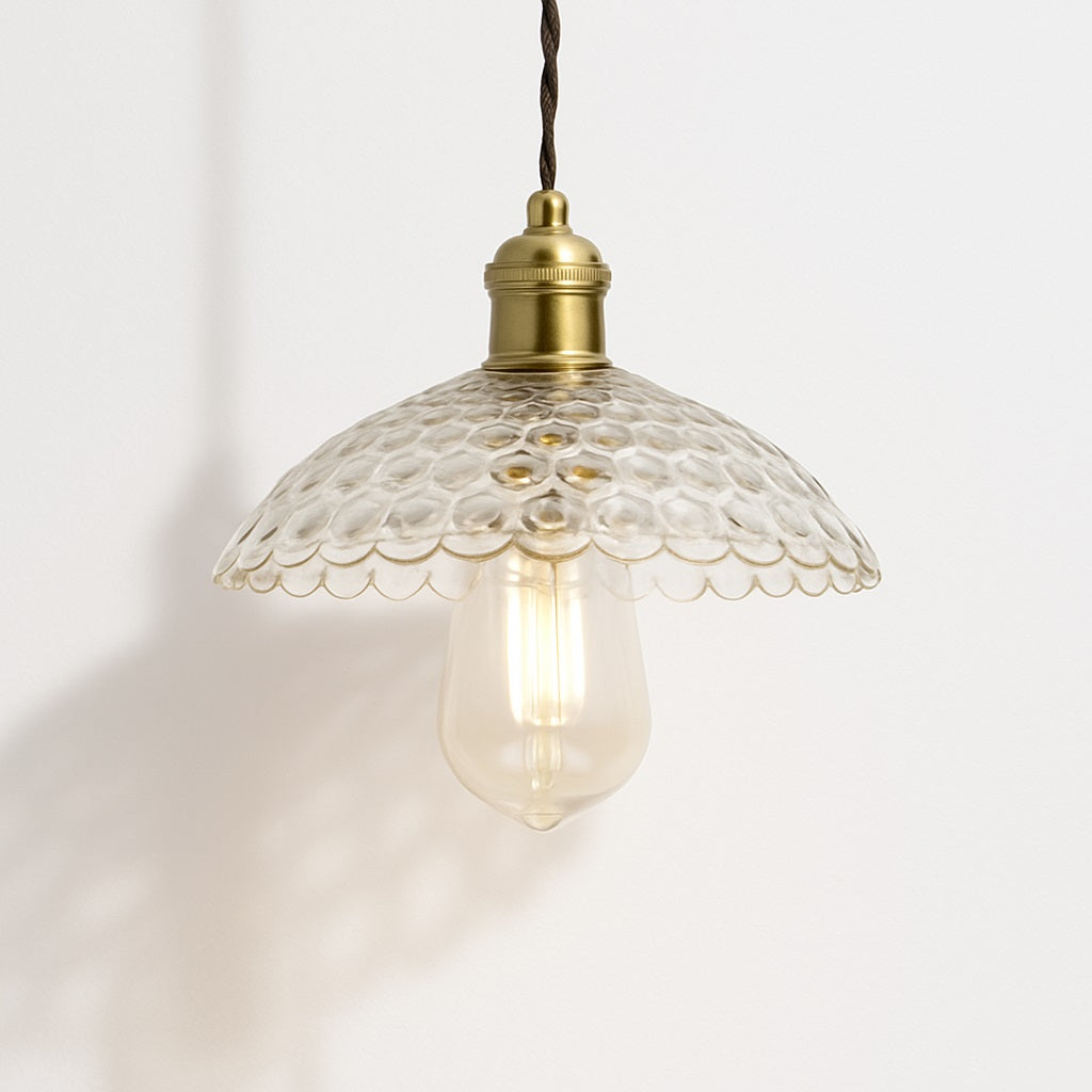 Suspension en verre transparent à reliefs ronds, bord festonné, douille laiton doré, design élégant et rétro.