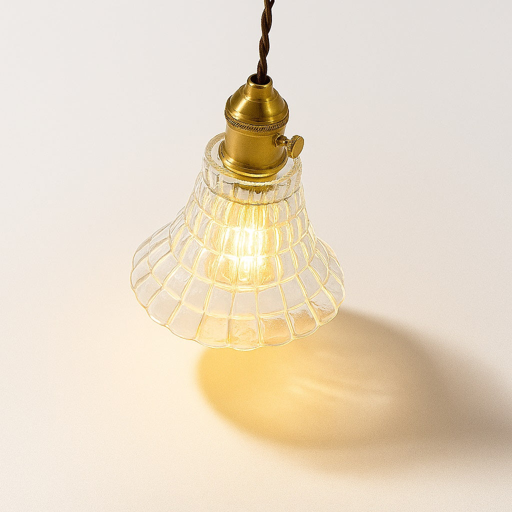 Lampe suspendue vue du dessus à 45°, abat-jour en verre nervuré forme fleur, douille laiton, éclairage chaleureux.