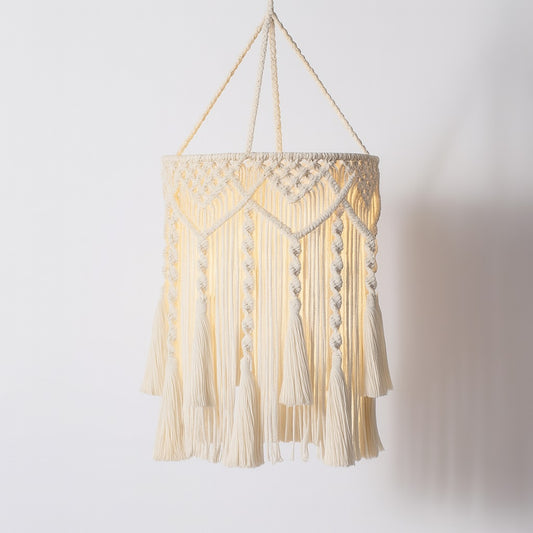 Suspension coton blanc tressé avec franges longues, motifs macramé et lumière chaude pour une lampe décorative bohème.