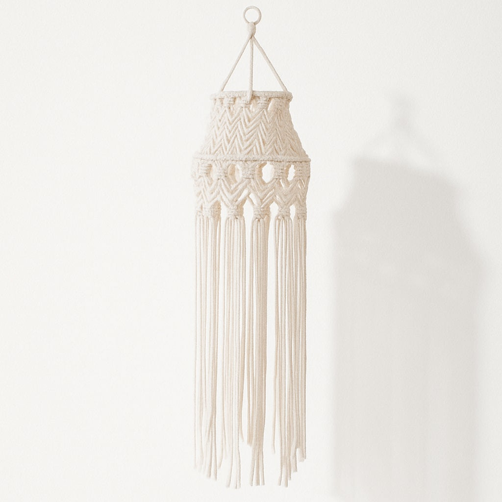 Suspension blanche en coton macramé avec longues franges tombantes, effet graphique et bohème sur fond blanc.