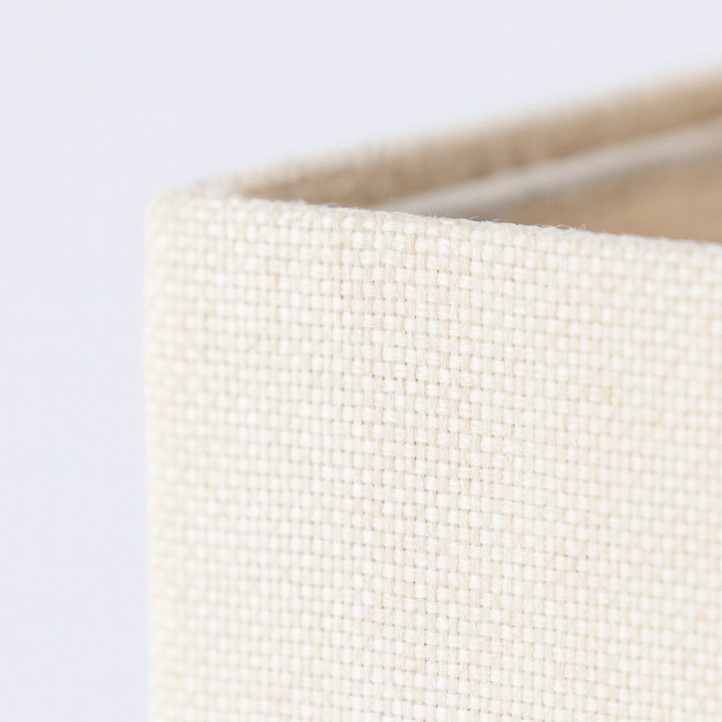 Gros plan sur le tissu d’un abat-jour carré amande, texture tissée fine pour abat-jour lampadaire raffiné.