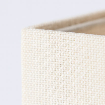 Gros plan sur le tissu d’un abat-jour carré amande, texture tissée fine pour abat-jour lampadaire raffiné.