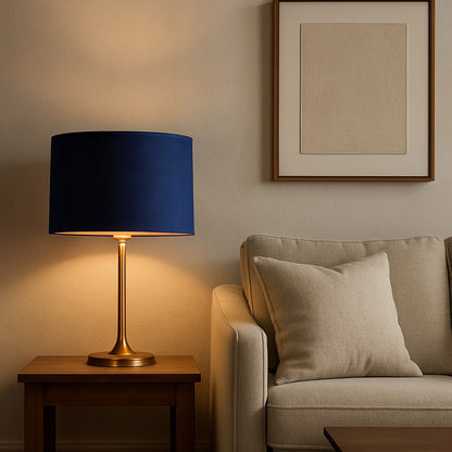 Lampe de chevet avec abat-jour ovale en velours bleu azur et intérieur doré, posé sur table en bois dans un salon moderne