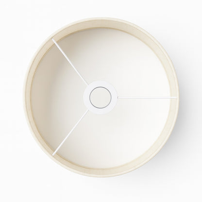 Vue du dessus d’un abat-jour tambour beige en tissu pour lampadaire, structure métallique blanche.