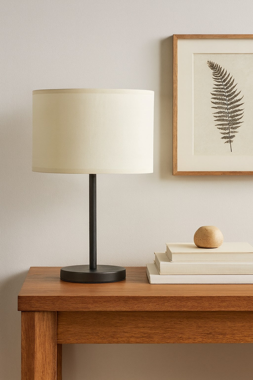Abat-jour tambour en lin blanc, posé sur lampe moderne noire, déco sobre et élégante avec cadre botanique.