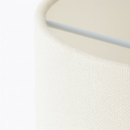 Abat-jour écru en tissu clair, gros plan sur la texture fine et le rebord pour illustrer un design textile élégant.