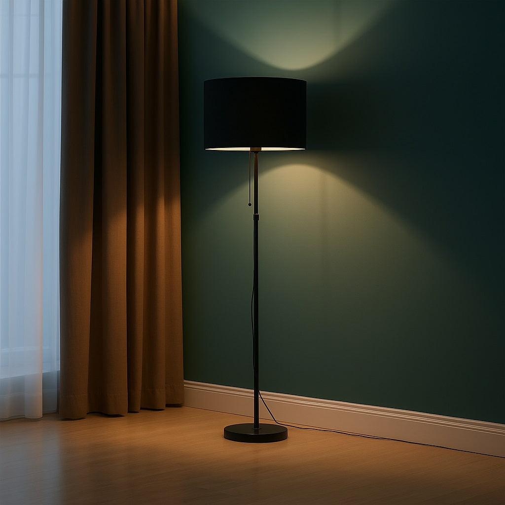 Lampadaire avec abat-jour noir tambour diffusant une lumière douce, idéal pour salon ou chambre.