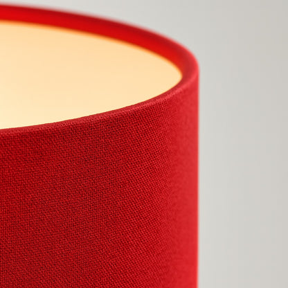 Détail tissu d’un abat-jour rouge en forme tambour, design moderne et chaleureux pour lampe décorative.