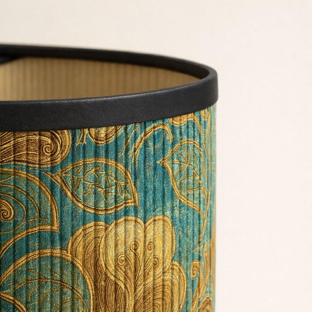 Zoom sur tissu d’abat-jour vert à motifs dorés, texture fine et reflets lumineux haut de gamme.