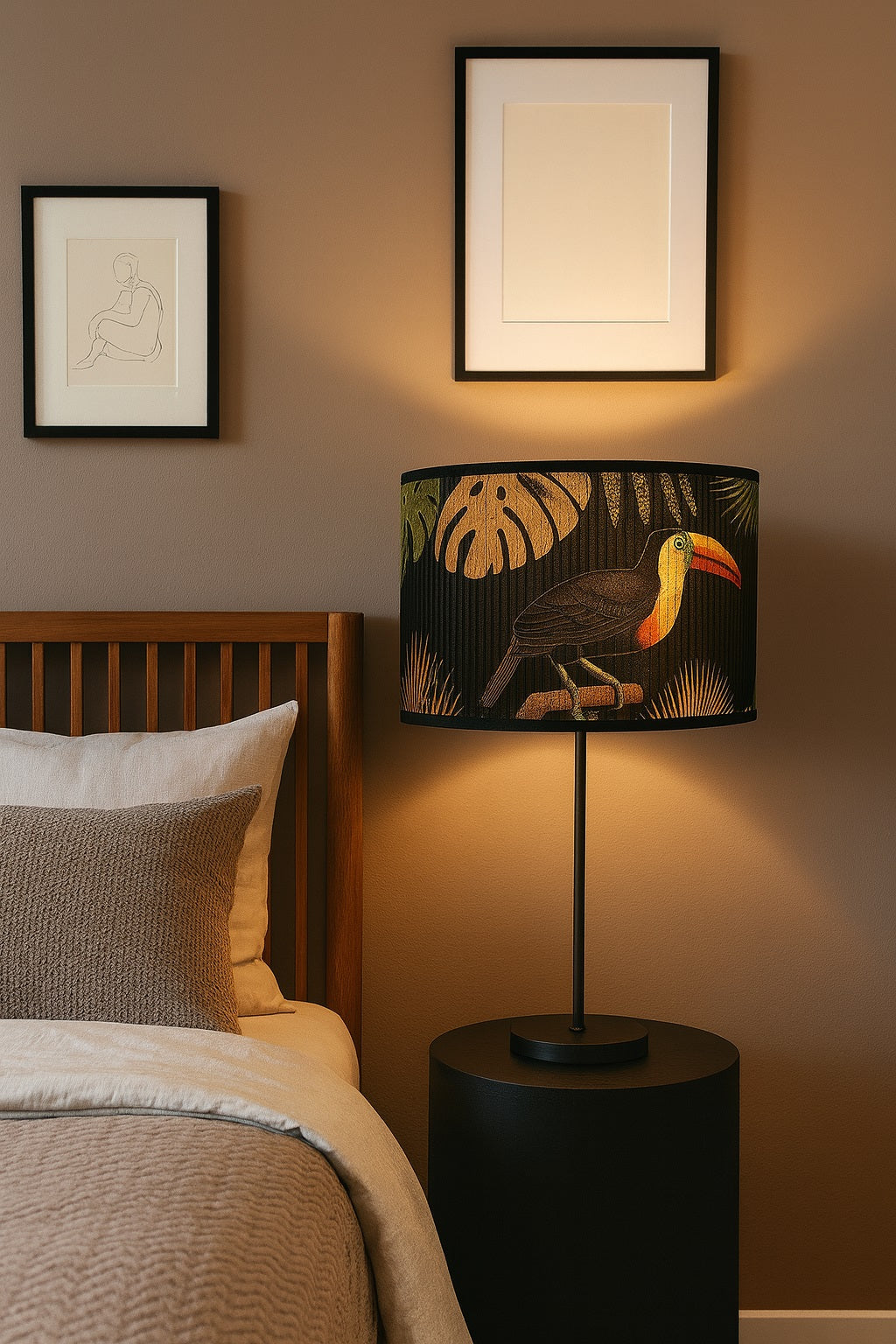 Lampe de chevet allumée avec abat-jour noir motif toucan exotique, ambiance chaleureuse et naturelle.