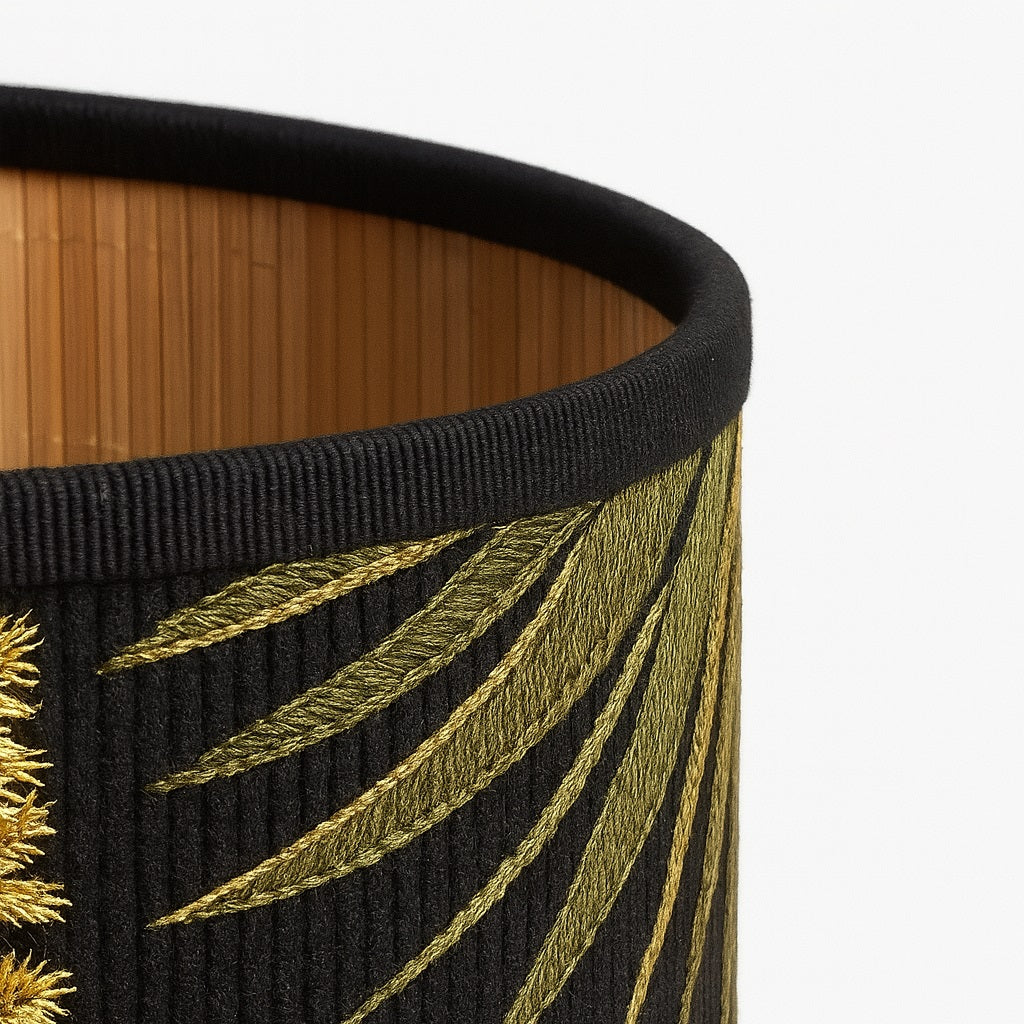 Gros plan sur la texture en bambou et broderie du motif toucan sur abat-jour noir pour lampe design tropicale.