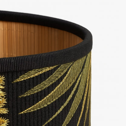 Gros plan sur la texture en bambou et broderie du motif toucan sur abat-jour noir pour lampe design tropicale.