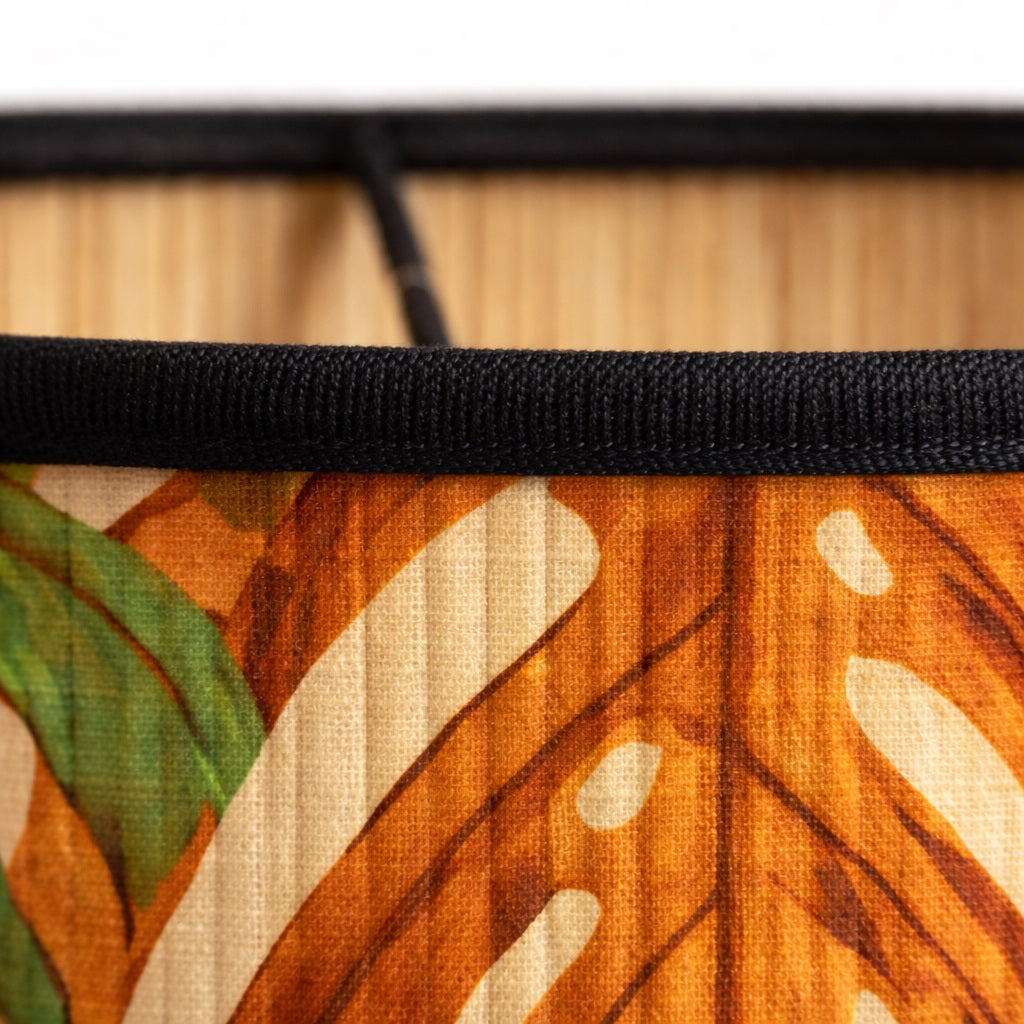 Gros plan sur abat-jour en bambou imprimé feuillage tropical, texture naturelle et finition soignée.