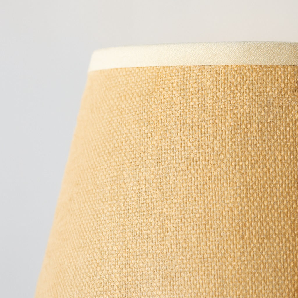 Détail d’un abat-jour conique en lin beige, texture naturelle et élégante pour lampe au style doux et chaleureux.