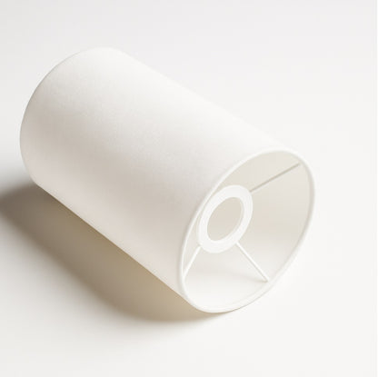 Vue en angle d’un abat-jour cylindrique en tissu blanc avec armature intérieure discrète