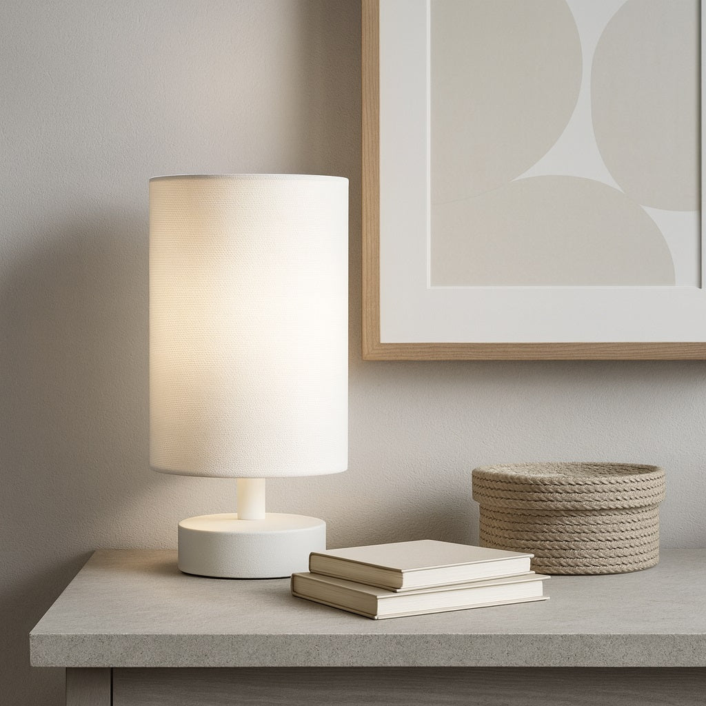 Abat-jour cylindrique beige posé sur un bureau élégant, éclairage doux et décor minimaliste assorti.