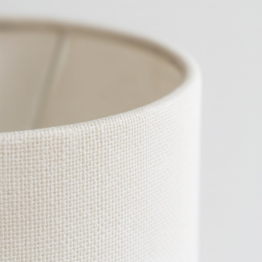 Gros plan sur un abat-jour en tissu beige clair, montrant la texture tissée.