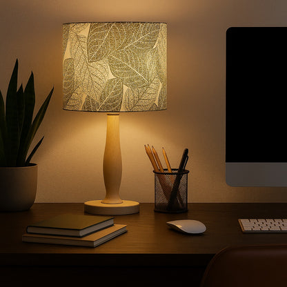 Lampe allumée avec abat-jour motif feuilles vertes, lumière douce idéale pour bureau ou coin lecture.