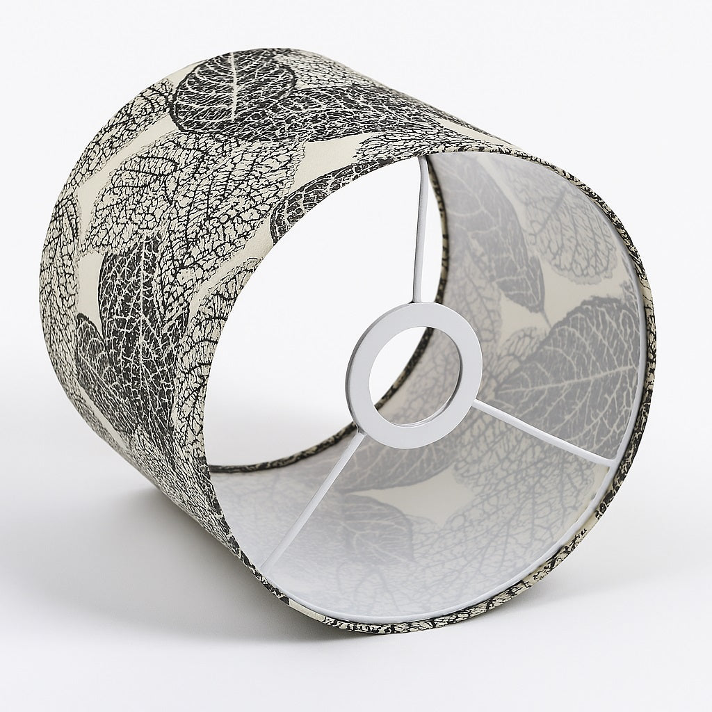 Abat-jour cylindrique en tissu beige imprimé de feuilles noires, vue latérale montrant la structure intérieure à trois branches.