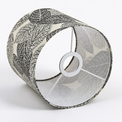 Abat-jour cylindrique en tissu beige imprimé de feuilles noires, vue latérale montrant la structure intérieure à trois branches.