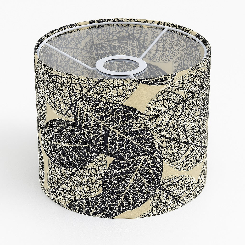 Abat-jour cylindrique en tissu beige décoré de feuilles noires, vue du dessus montrant la structure métallique intérieure.