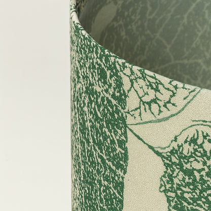 Zoom détaillé sur tissu d’abat-jour vert à motif feuilles, texture fine et finition haut de gamme.