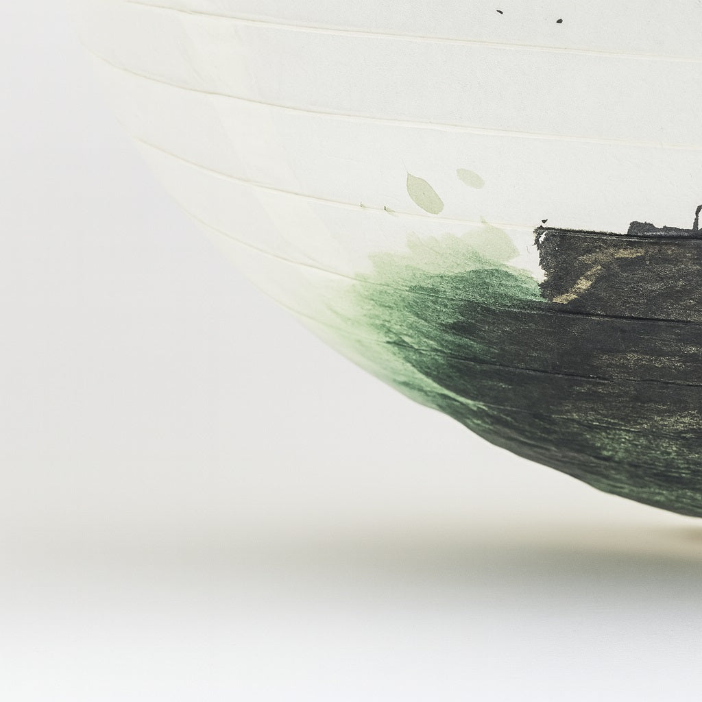Gros plan sur un abat-jour en papier japonais illustré d’un tronc de bonsaï peint à l’encre, rendu artisanal.