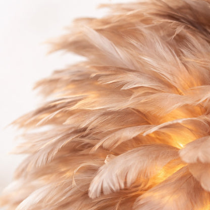 Abat-jour en plumes naturelles, gros plan sur la texture aérienne et la lumière chaleureuse diffusée
