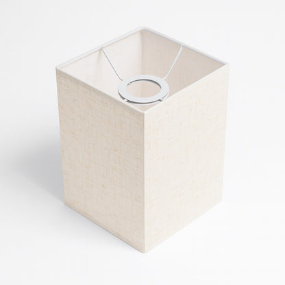 Abat-jour rectangulaire en tissu ivoire texturé, avec armature blanche, design sobre et naturel.