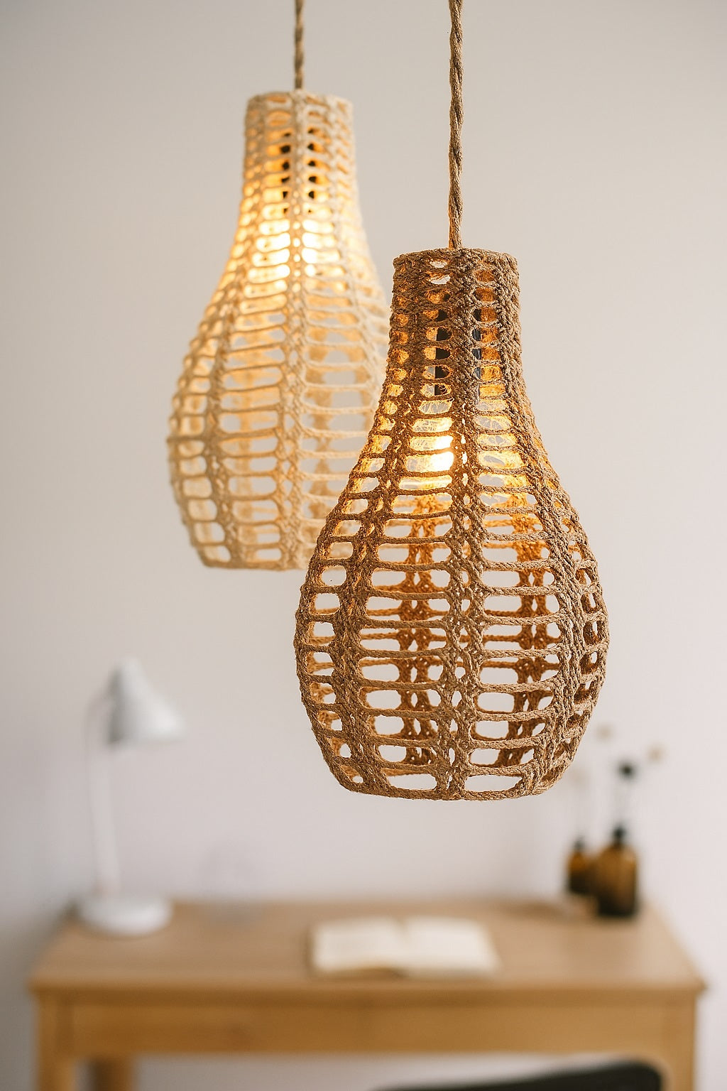 Suspension en corde tressée naturelle allumée, suspendue au-dessus d’un bureau en bois dans un intérieur minimaliste – ambiance chaleureuse et déco bohème, luminaire E27 tendance signé Monsieur Abat-Jour.