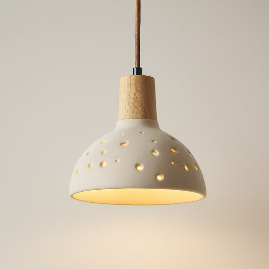 Abat-jour suspension en ciment perforé et bois clair, lumière douce et effet constellation, style naturel et contemporain.