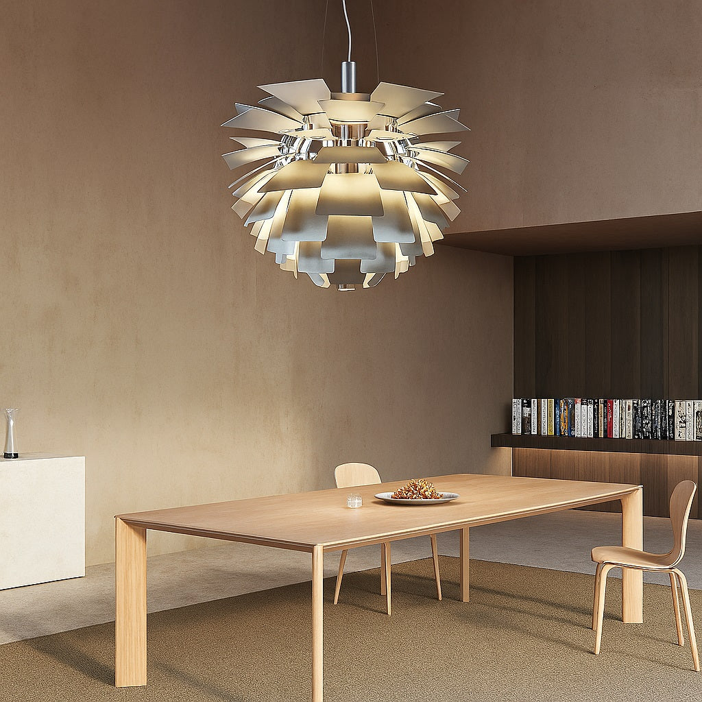 Suspension design chromée au-dessus d’une grande table en bois clair dans une salle à manger moderne au décor minimaliste.