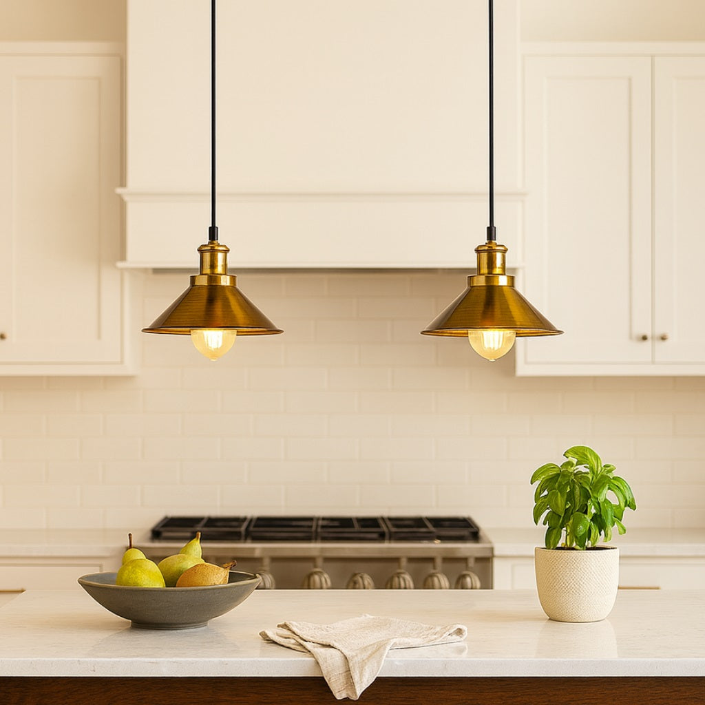 Abat-jour suspension en métal doré au-dessus d’un îlot de cuisine moderne, ambiance lumineuse chaleureuse.