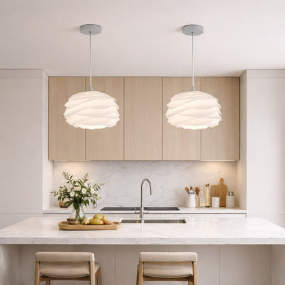 Abat-jour suspension blanc au design sculptural, installé au-dessus d’un îlot de cuisine moderne et épuré