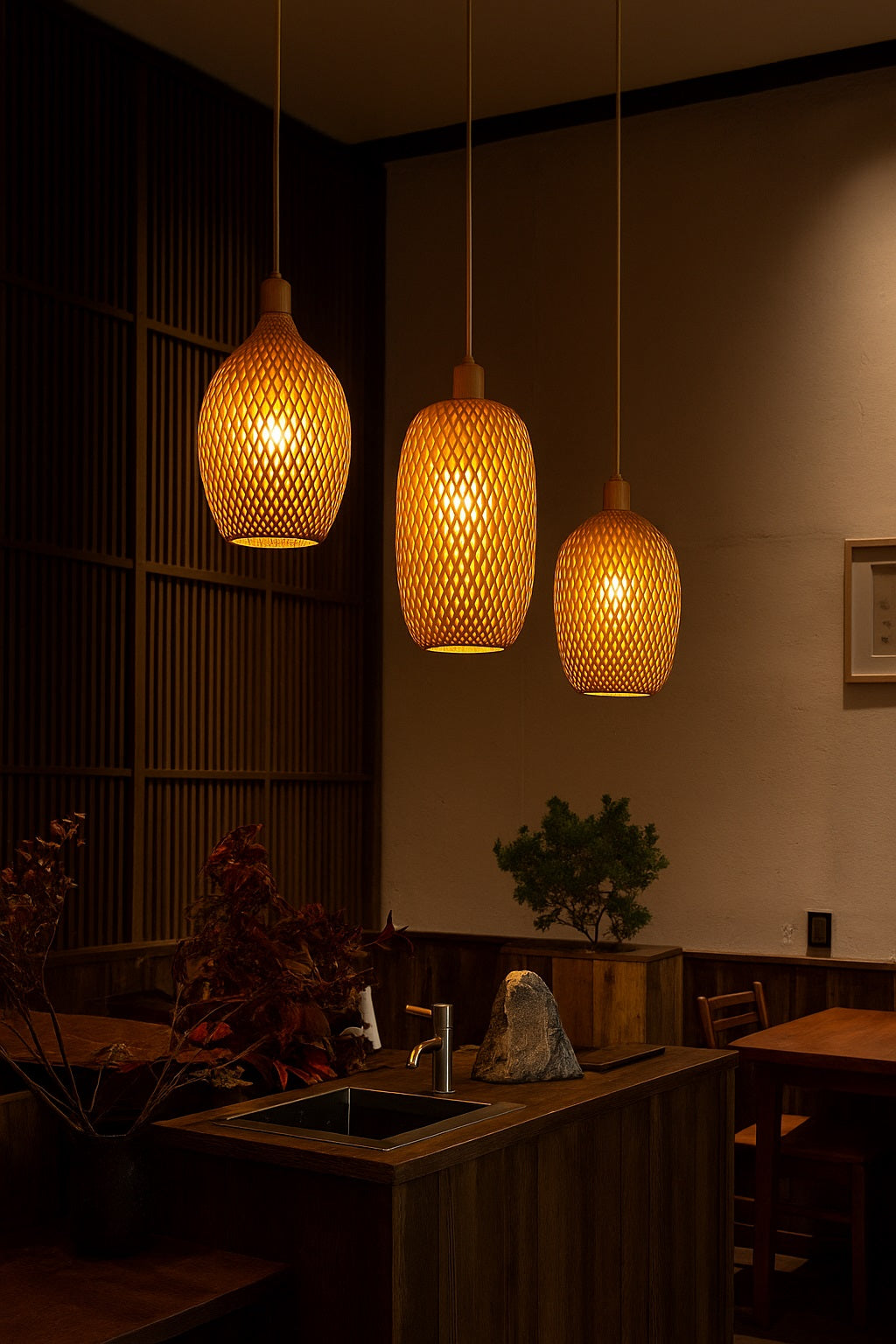 Suspensions en rotin ajouré diffusant une lumière chaleureuse au-dessus d’un îlot de cuisine en bois dans un décor naturel et zen