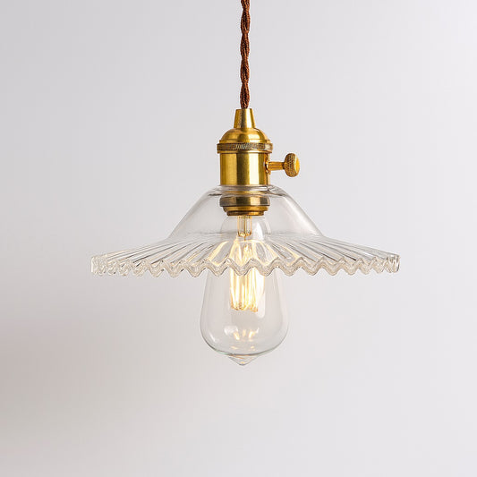Lampe suspension en verre nervuré transparent avec douille dorée et ampoule LED apparente.