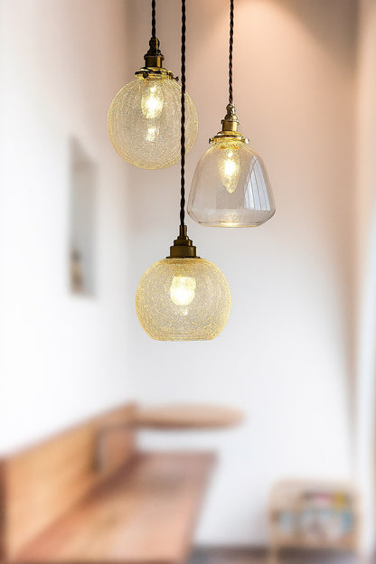 Suspensions en verre nettes brillent au premier plan, avec un flouté d'un coin repas chaleureux.